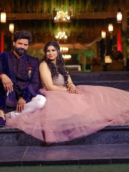 A stylish portrait of the engaged couple seated on the steps of the venue, showcasing their outfits and the grand setting.