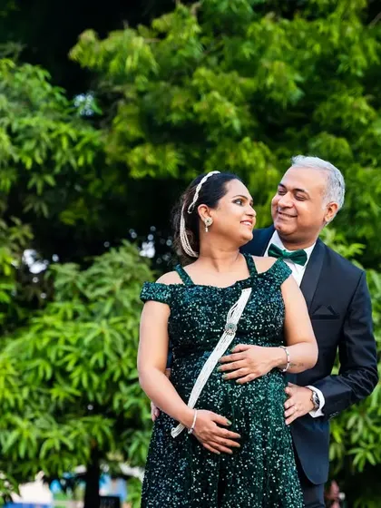 Taking the formal look outdoors creates a wonderful contrast. The elegant green sequin gown and tuxedo stand out against the natural green background for a unique and stylish maternity photo.