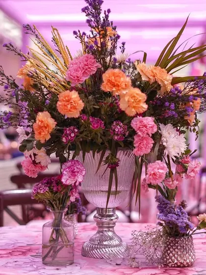 A close-up of a stunning floral centerpiece. We used a mix of carnations, roses, and other seasonal flowers in shades of pink, peach, and purple to create a lush and romantic arrangement.