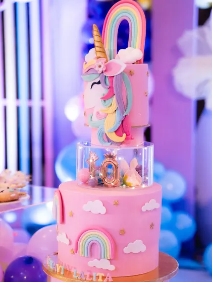 A birthday isn't complete without a cake. This multi-tiered unicorn cake was the centerpiece of the dessert table, surrounded by pastel balloons and rainbow decorations.