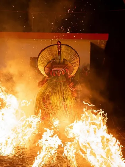 Close-up and action shots of the Kandanar Kelan Theyyam, focusing on the detailed costume, expressive mask, and the raw power of the fire performance.