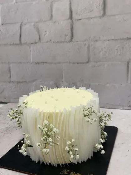 Simplicity at its finest. This elegant white cake is decorated with a delicate rice paper sail effect and sprigs of fresh baby's breath. It’s perfect for a bridal shower, engagement, or any minimalist celebration.