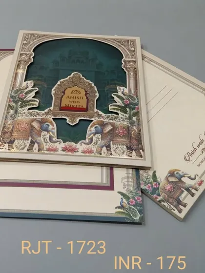 A multi-layered invitation with a die-cut archway revealing a deep teal background. The design is framed with royal elephants and floral patterns, and includes three inserts for event details.
