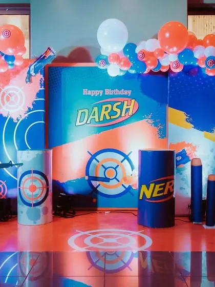 The full view of the action-packed Nerf Gun party stage. The setup includes balloon columns, target-themed floor decals, and a silhouette of a soldier for a complete battle zone feel.