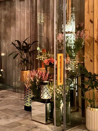 A beautifully styled corner in our indoor hall, with floral arrangements and lanterns on mirrored tables.