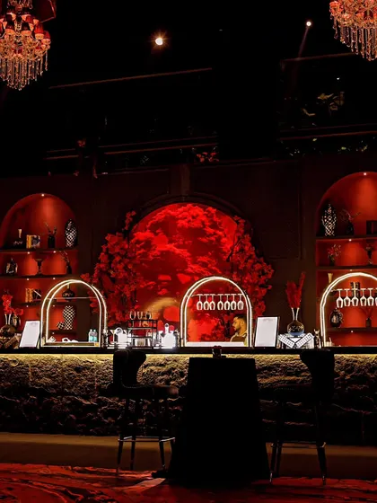 A stunning bar setup for the "Red Royal Affair." The arched back-bar, filled with a mass of red roses and illuminated to create a powerful focal point, served as the heart of the party.