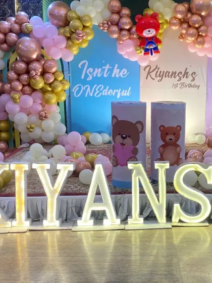 A close-up of the 'KIYANSH' marquee letters and the themed cylindrical stands used as props on the birthday stage.