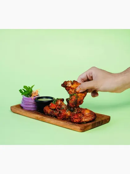 This shot captures a hand picking up a chicken wing, creating a relatable and appetizing moment. It’s an effective way to showcase finger foods.