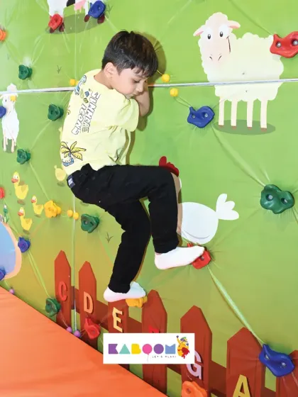 This little climber is determined to make it to the top of our colorful and safe climbing wall. It's a great activity for building confidence and strength.