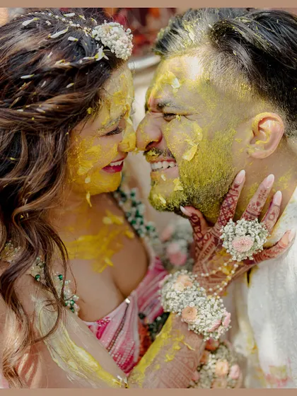 A close-up of the couple's faces covered in turmeric and smiles during their haldi, a moment of pure, messy joy.