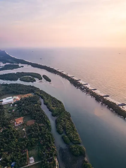 An aerial view of the Karavali coast, showcasing the serene beauty of the shoreline where lush greenery meets the vast expanse of the Arabian Sea.