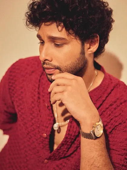 A close-up portrait of Siddhant. The textured fabric of the kurta adds depth and interest to the monochrome red look.