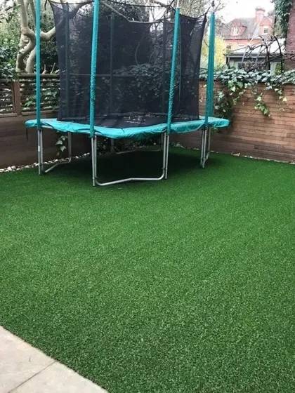 This backyard is always ready for fun with a sturdy artificial grass installation. It’s tough enough to handle a trampoline and frequent use while maintaining its lush, green appearance.