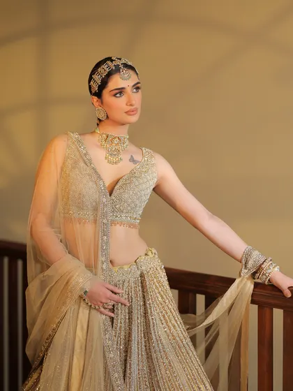 A modern take on a golden lehenga, featuring a unique headband-style maang tikka and a plunging neckline blouse.