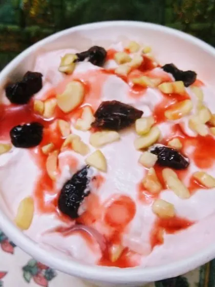 A creamy and delicious plant-based dessert, possibly a vegan shrikhand, topped with nuts, raisins, and a sweet syrup.