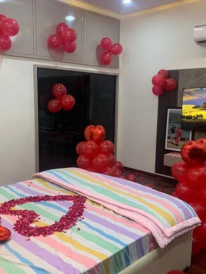 A cozy and romantic room decoration with red balloons and a heart made of rose petals on the bed. This simple yet effective setup is perfect for a birthday or anniversary surprise.