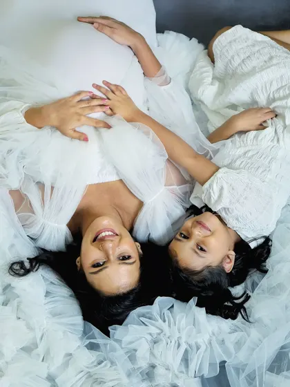 An artistic top-down shot showing the beautiful connection between a mother and daughter. The flowing white fabric creates a soft, dreamy atmosphere for this maternity portrait.
