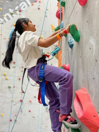 A young girl confidently scales the wall. Our goal is to empower kids and show them they can achieve anything they set their minds to.