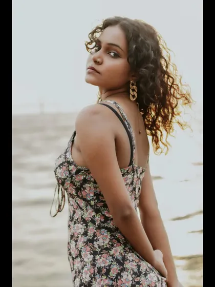 A classic over-the-shoulder look with a strong, confident expression. The backlighting from the sun highlights the model's curly hair, adding texture to the portrait.