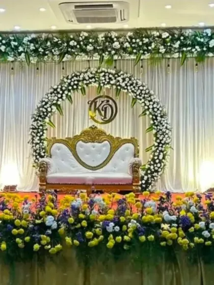 A close-up of the monogrammed stage, showing the detail in the floral arrangements of yellow marigolds, white chrysanthemums, and purple asters.