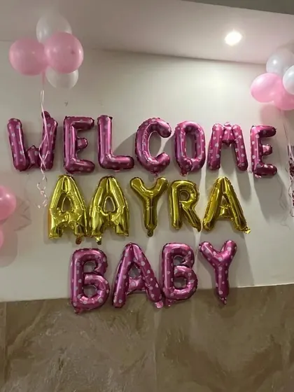 I can personalize the welcome message with your baby's name. This setup for baby Aayra uses a mix of pink and gold foil balloons to make her feel extra special.
