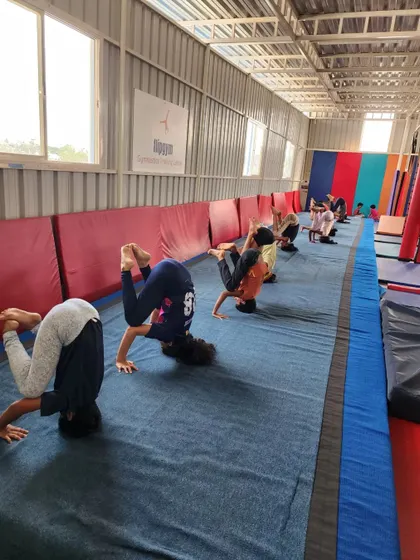 Building strength and balance from an early age, these young gymnasts practice their headstands in a group setting, encouraging each other.
