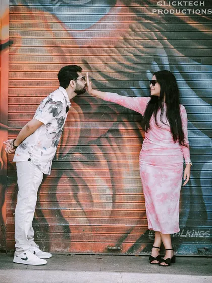 A duplicate of a playful and artistic shot of a couple posing against a colorful graffiti wall.