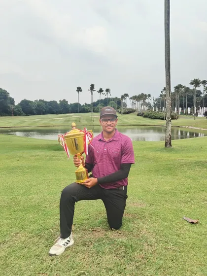 Harman kneels with his impressive winner's trophy on the course in Jakarta after winning the 4th International Jr Menpora PAGI EMERALDA Golf Championship.