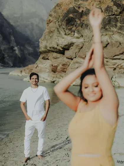 A candid, fun moment captured at the riverside in Rishikesh. The focus on the groom's reaction to his dancing partner makes this shot feel genuine and full of life.