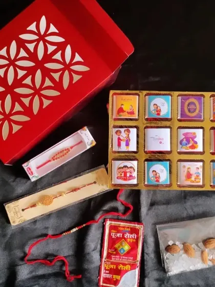 A Rakhi gift set featuring a box of assorted custom-wrapped chocolates, multiple rakhis, and a packet of roli-chawal with almonds.