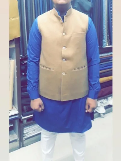 A classic look with a beige Nehru jacket over a royal blue kurta. This is a timeless and versatile combination for any festive occasion.