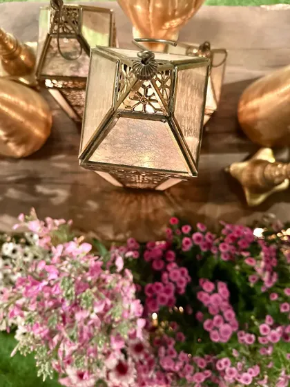 An artistic top-down shot of a brass lantern and fresh pink flowers.