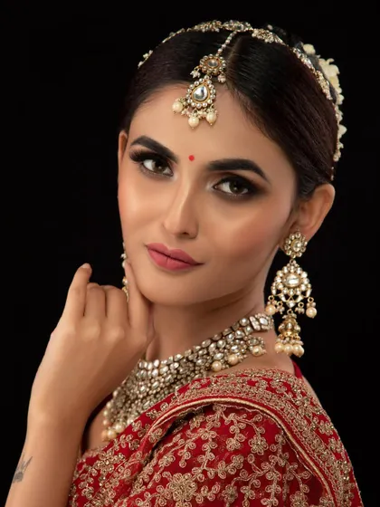 A close-up of a model wearing a beautiful Kundan and pearl matha patti and choker set. The intricate details make this a truly special piece.