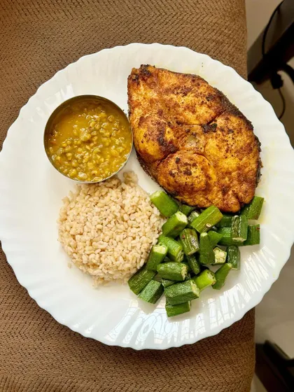 This high-protein plate features a large piece of pan-fried kingfish, served with broken wheat, dal, and sautéed okra.