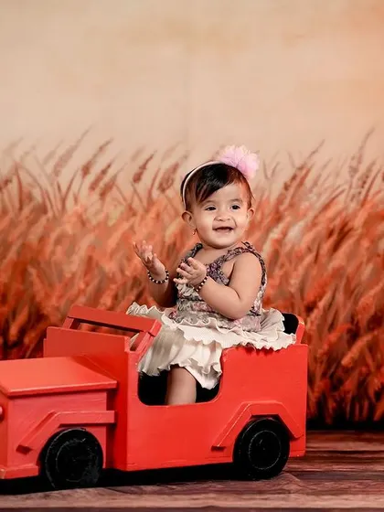 A happy girl in her red car, driving through a rustic field. The warm lighting creates a beautiful, nostalgic feel.