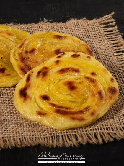 This shot of Malabar parathas focuses on their unique layered and flaky texture. The simple burlap background adds a rustic touch that complements the bread.