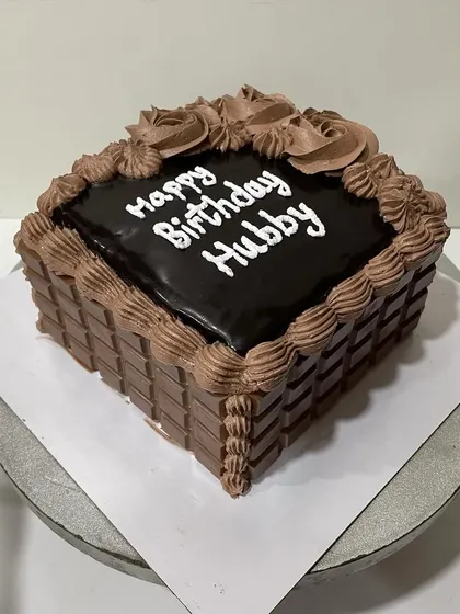 Another angle of the square chocolate cake, showing the detailed piping and chocolate bar decoration.