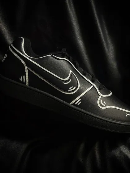 A pair of black Nike Ebernon sneakers with the same bold, white-outline cartoon effect.