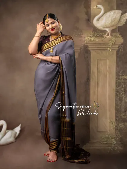 A graceful pose in a grey saree, set against a classical backdrop with swan figures for an artistic touch.