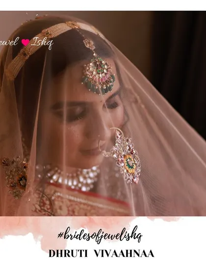A shy glance from the bride under her veil. This shot highlights her custom-designed meenakari nath and mathapatti, which were created to perfectly complement her heirloom necklace.