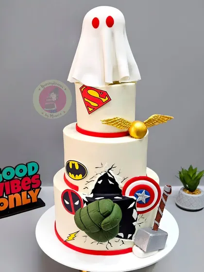 A three-tier cake made for The Souled Store's anniversary, featuring their iconic ghost logo alongside superhero and Harry Potter symbols.