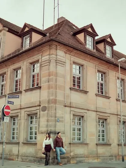 A wide-angle view of the couple posed against a corner building, showcasing the charming, old-world architecture of the German town.