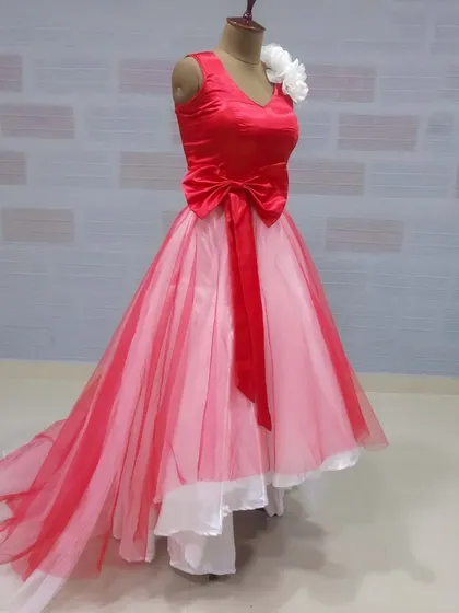 This side view shows the high-low design and attached trail of the red and pink gown. It's a playful and stylish option for a birthday party, pre-wedding shoot, or other celebration.