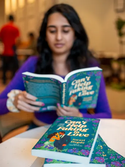 Reading a copy of "Can't Help Faking in Love" at a cafe. This book is set in Bangalore and is a closed-door, fake-dating romance.