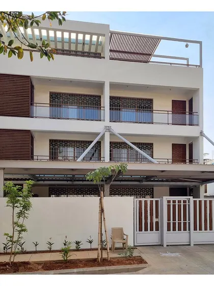 The finished facade of the contemporary residence, showing the interplay of the white structure, wooden screens, and a modern gate design.