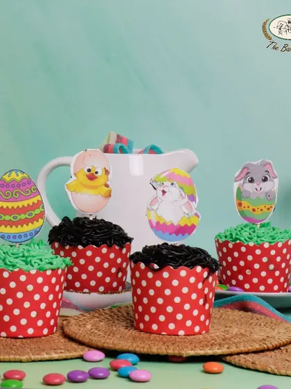 Our assorted Easter cupcakes come in vanilla, chocolate, and butterscotch flavors. They are topped with festive paper decorations featuring bunnies and eggs, perfect for an Easter party.