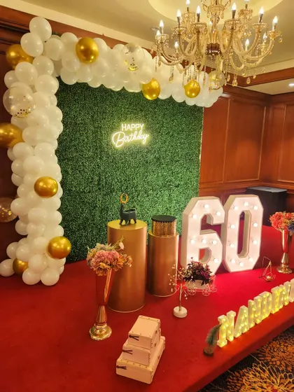 Another elegant 60th birthday, this time with a greenery wall backdrop, a white and gold balloon arch, and personalized marquee letters.