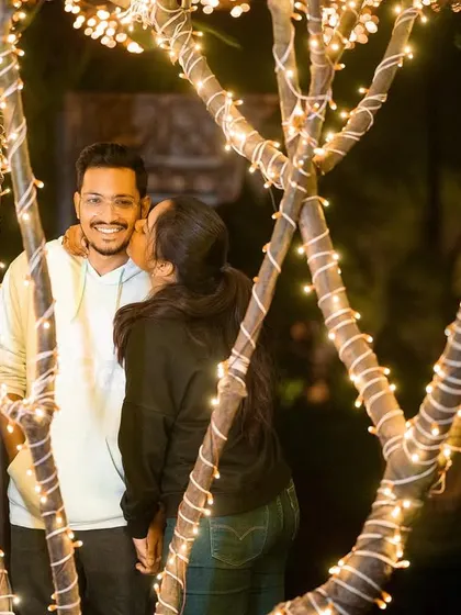 A candid and happy moment captured at night, with trees wrapped in lights creating a beautiful backdrop.