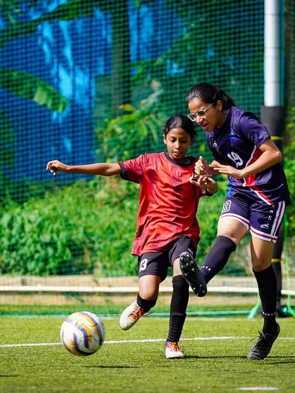 A young player bravely goes in for a tackle, fighting to win the ball back for her team in a crucial moment.