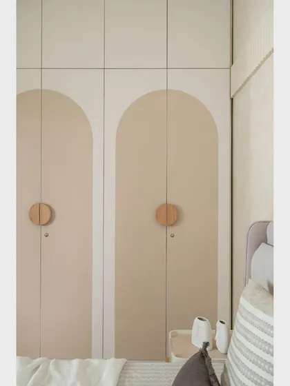 The wardrobe in the guest bedroom features arched panels and simple wooden knobs, echoing the curved design language seen throughout the home.